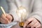 Business person writing notes,ideas,creative brainstorming with shining lightbulb