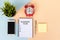 Business Plan text on Note Pad with alarm clock, smart phone, pen and potted plant on multi colored background