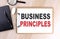 BUSINESS PRINCIPLES text on clipboard on wooden background