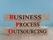 Business Process Outsourcing symbol. Brick bkocks with red words BPO. Beautiful blue background. Wooden table. Business and BPO