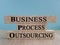 Business Process Outsourcing symbol. Brick bkocks with words BPO. Beautiful blue background. Wooden table. Business and BPO