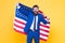 Business professional. Successful business owner holding american flag on yellow background. Happy business man