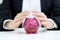 Business savings concept - businesswoman covering piggy bank wit