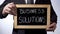Business solutions written on blackboard, businessman holding sign, strategy