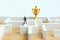 Business strategy conceptual photo - Miniature of businessman on a labyrinth maze seeking the golden trophy
