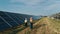 Business team of industrial engineers walking on solar farm and discussing efficient plan of construction. Three