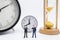 Business and Time management Concept. Close up of two businessman miniature figure standing with vintage alarm clock and sandglass