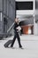 business tourism, business woman in a formal suit with a smartphone in a business center or airport with a suitcase goes