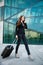 Business travel - woman with suitcase walks outside airport building