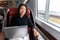 Business trip Asian woman working on laptop on train commute travel lifestyle. Middle aged chinese businesswoman smiling