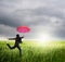 Business umbrella woman jumping to riancloud in grassland with red umbrella