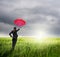 Business umbrella woman standing to riancloud in grassland with red umbrella