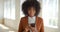 Business woman with afro using phone, thinking and texting negotiation deals to clients. Funky, cool and confident