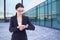 Business woman checks time on her wrist watch standing on street