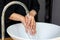 Business woman in dark black suit is washing her hand in sink