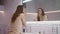 Business woman doing makeup in bathroom. Beauty female person looking at mirror.