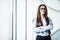 Business woman in formal clothes and eyesglasses in office with panoramic windows.