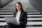 business woman in a formal suit with a laptop in an office or business center sits on the steps in the lobby and works