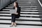 business woman in a formal suit with a laptop in an office or business center sits on the steps in the lobby and works