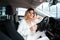 Business woman with a glass of champagne sits in her new car in a dealership. Girl celebrates the purchase of a new car