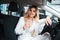 Business woman with a glass of champagne sits in her new car in a dealership. Girl celebrates the purchase of a new car