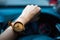 business woman hand wearing wooden wrist watch. her holding steering wheel car for driving and have car interface status are back