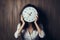 Business woman hides face behind clock, symbolic of time pressure