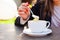 Business woman holding cup of cappuchino on outdoors cafe, close up