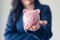 Business Woman Investor Holding Piggy Bank for Money Savings on Her Hands, Asian Businesswoman in Uniform Suit Showing Money