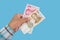 Business woman`s hand holds 100 and 20 yuan banknotes isolated on blue background. Money in a woman`s hand. Chinese money.