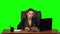 Business woman sitting at a desk writes a message on a cell phone with rage. Green screen. Studio. Slow motion