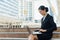 Business woman smile and sit on the staircase and typing word into laptop