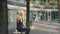 Business woman speaking on phone and waving with hand. Elegant modern woman sitting on bench and waving with hand to