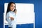 Business woman is standing in office and is writing on white board