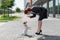 Business woman in a suit and high heels is training a puppy of Jack Russell Terrier on the street. A small dog fulfills