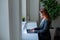 Business woman typing on laptop while sitting in a cafe by the window. A female manager in a suit remotely works during