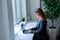 Business woman typing on laptop while sitting in a cafe by the window. A female manager in a suit remotely works during