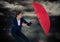 Business woman with umbrella blocking rain against storm clouds