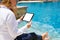 Business woman using tablet computer by the pool