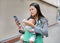 Business woman using telephone with carrying her infant and feeding her child`s by milk bottle. Busy mother hurrying in the