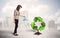 Business woman watering green recycle sign tree on city background