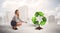 Business woman watering green recycle sign tree on city background