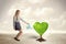 Business woman watering heart shaped green tree