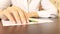 Business woman wearing white shirt sitting by the table with a piece of paper and a pencil and tapping fingers