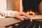 Business woman working on laptop, sitting near cozy fireplace at home. Focus on hands typing on keyboard. Social