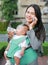 Business woman working by telephone with carrying her infant and feeding her child`s by milk bottle. Busy mother hurrying in the