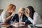 Business woman writing a document and two female coworkers gossiping in her ears