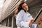 Business young caucasian woman intently looks at smartphone screen standing on street.