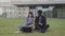 Businesslady sitting on grass outside and showing something on phone her African-American colleague