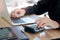 Businessman or accountant hands using calculator and laptop computer to calculate financial data, cost and budget on desk at